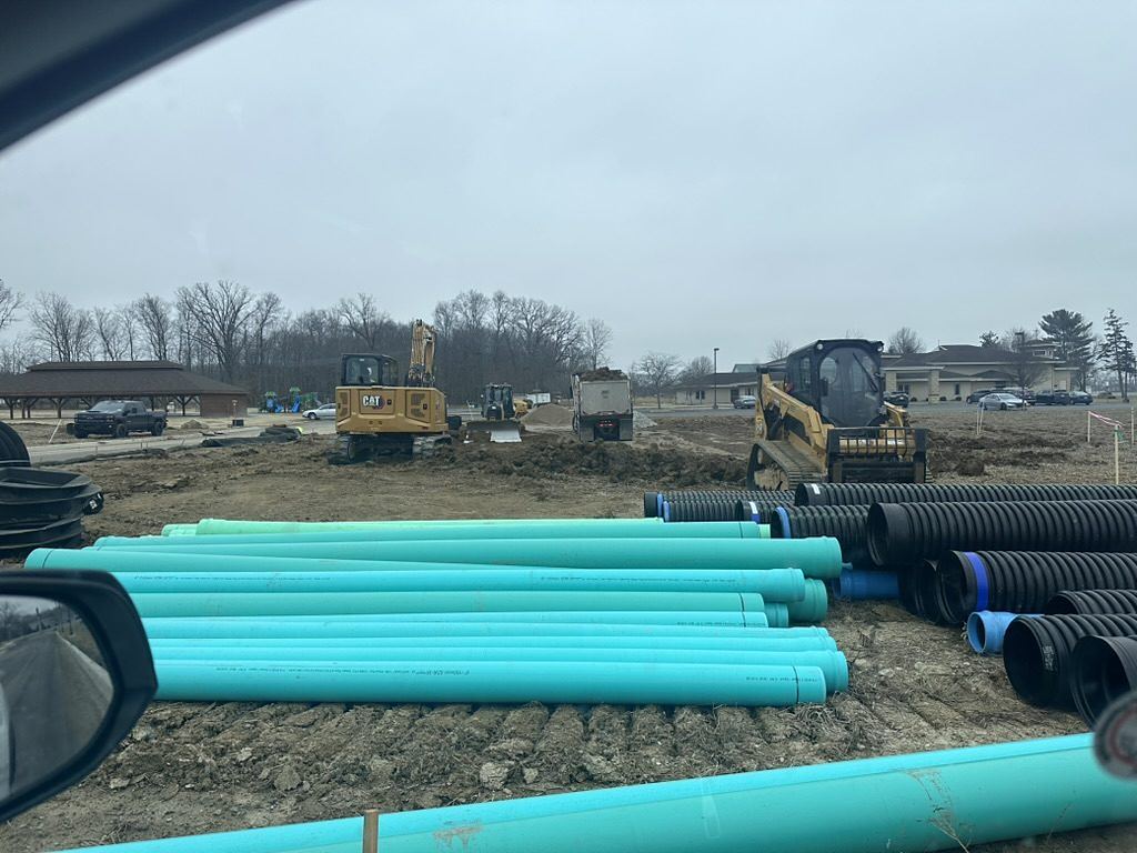 Green sanitary PVC and black HDPE storm pipe staged on a BDX jobsite